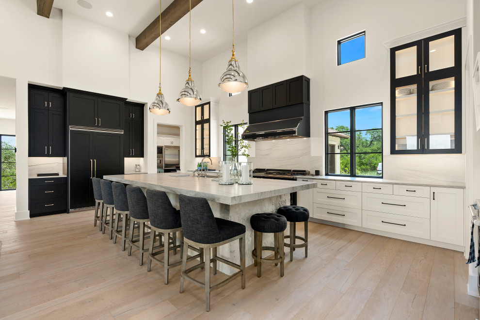Inspiration for a huge l-shaped light wood floor open concept kitchen remodel with white cabinets, white backsplash, marble backsplash, an island and black appliances