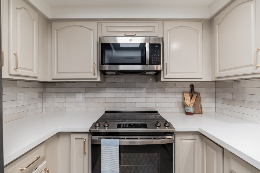 This is an example of a small contemporary l-shaped kitchen in Phoenix with raised-panel cabinets, beige cabinets, engineered stone countertops, beige splashback, porcelain splashback, stainless steel appliances, a breakfast bar and white worktops.