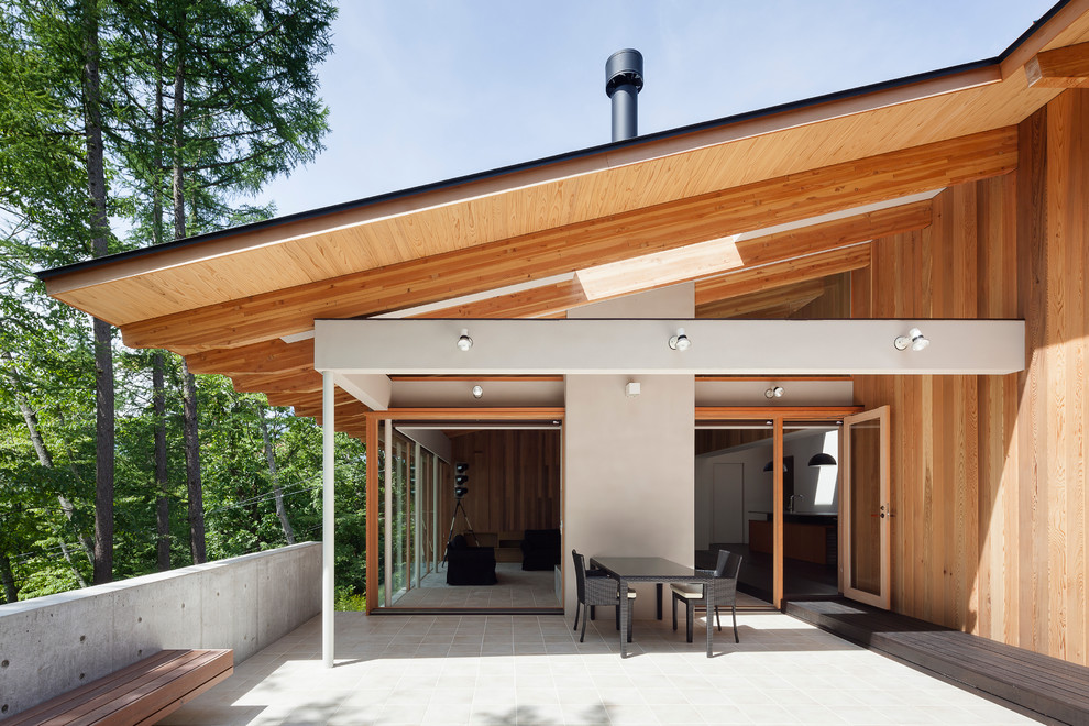 This is an example of a large contemporary backyard patio in Other with a roof extension.