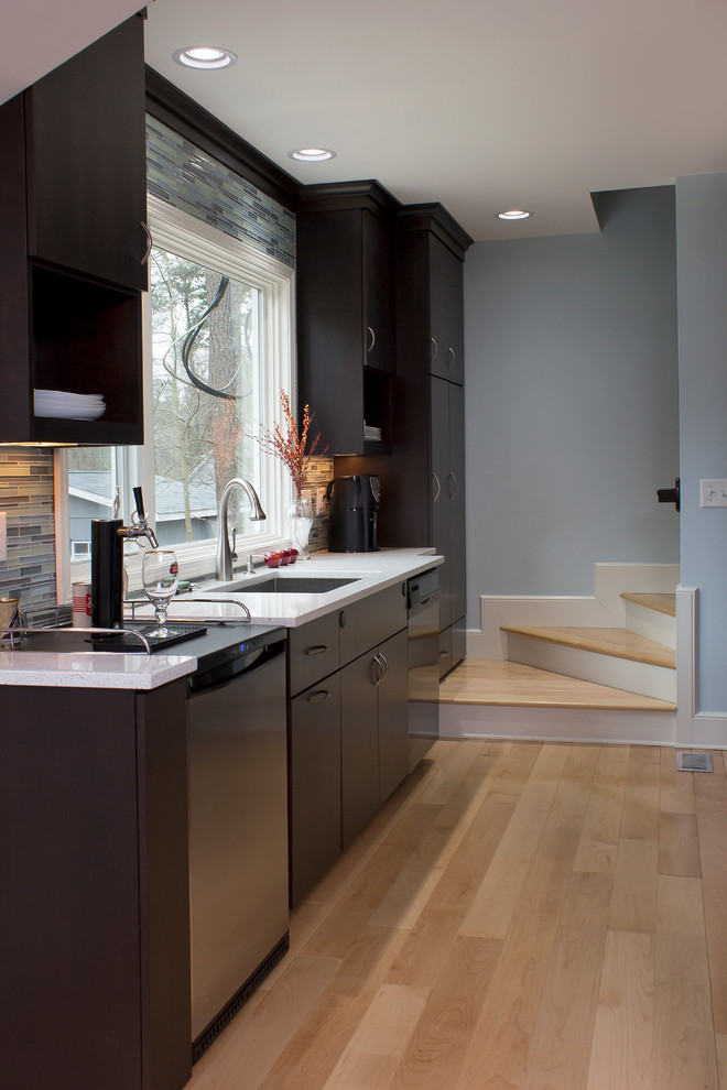Photo of a large contemporary u-shaped open plan kitchen in Raleigh with a single-bowl sink, flat-panel cabinets, dark wood cabinets, quartz benchtops, multi-coloured splashback, glass tile splashback, stainless steel appliances, light hardwood floors, with island, yellow floor and white benchtop.