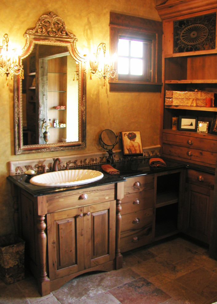 Inspiration for a mid-sized rustic master beige tile travertine floor and beige floor bathroom remodel with shaker cabinets, medium tone wood cabinets, yellow walls, a drop-in sink and granite countertops