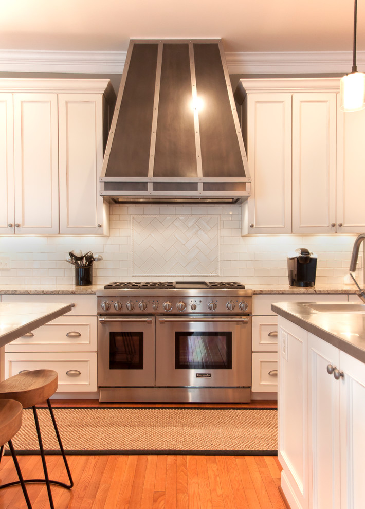 Example of a large transitional medium tone wood floor kitchen design in DC Metro with an undermount sink, white cabinets, granite countertops, white backsplash, ceramic backsplash and stainless steel appliances