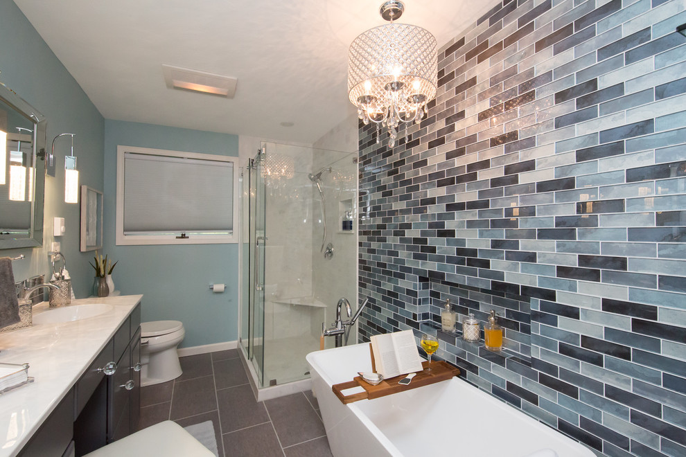 Mid-sized modern master bathroom in Other with raised-panel cabinets, grey cabinets, a freestanding tub, a corner shower, a bidet, blue tile, glass sheet wall, blue walls, an integrated sink, marble benchtops, grey floor and a sliding shower screen.