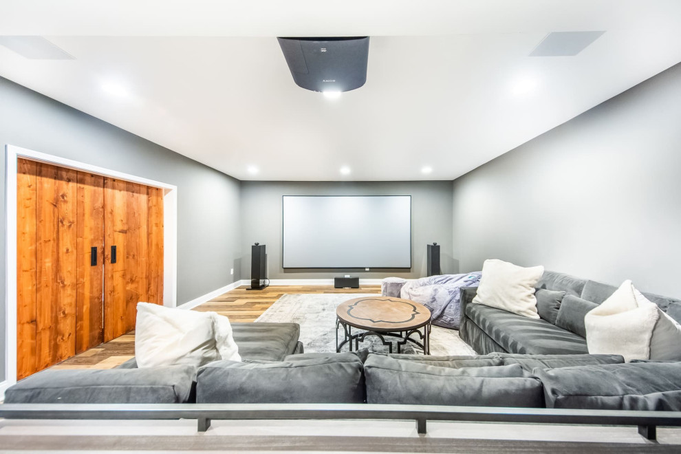 Mid-sized transitional enclosed home theatre in DC Metro with grey walls, vinyl floors, a projector screen and brown floor.