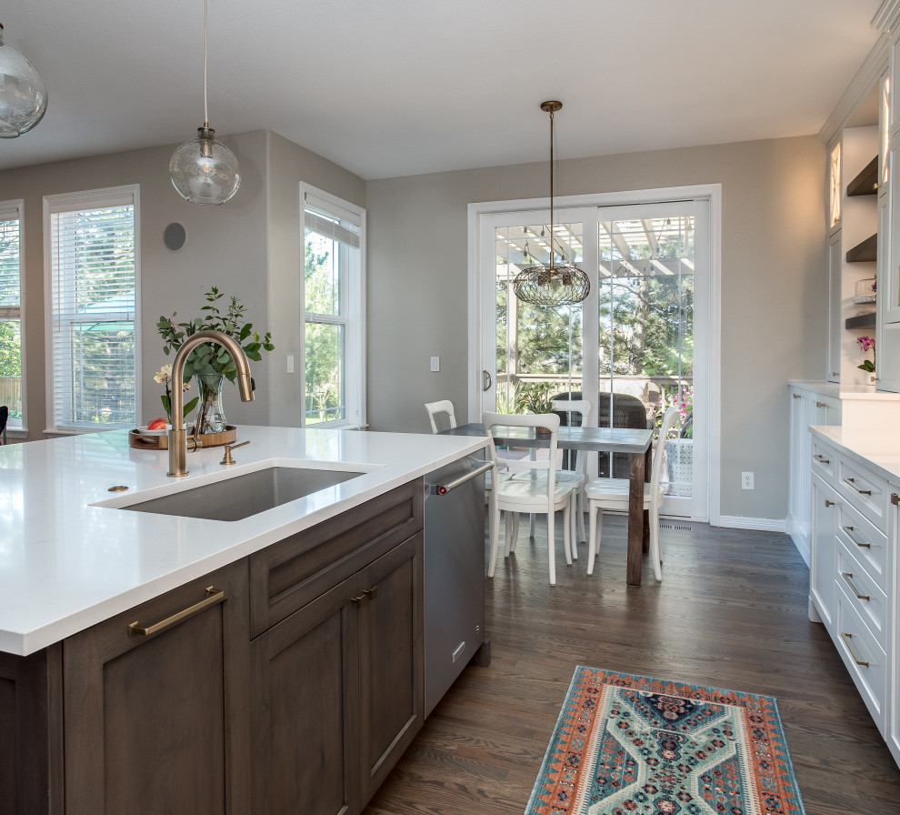 Example of a large transitional galley medium tone wood floor and brown floor open concept kitchen design in Denver with an undermount sink, shaker cabinets, white cabinets, quartz countertops, beige backsplash, marble backsplash, stainless steel appliances, an island and white countertops