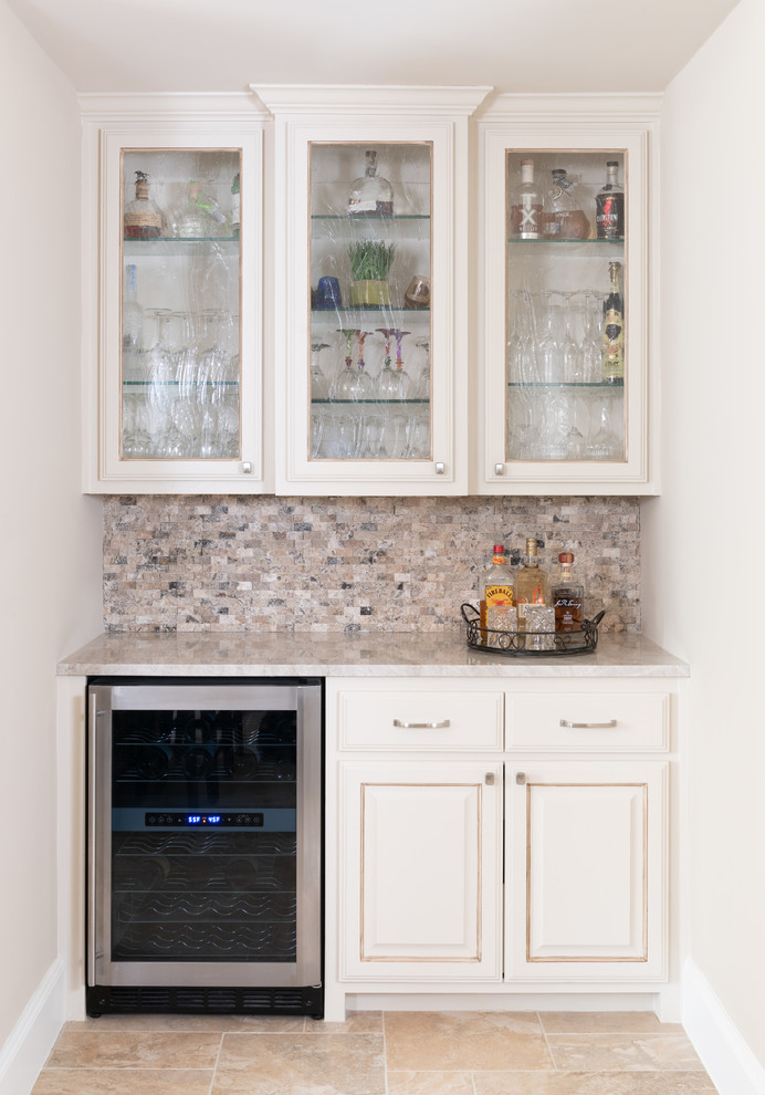 This is an example of a mid-sized traditional u-shaped home bar in Dallas with raised-panel cabinets, beige cabinets, quartzite benchtops, beige splashback, marble splashback, travertine floors, beige floor and beige benchtop.