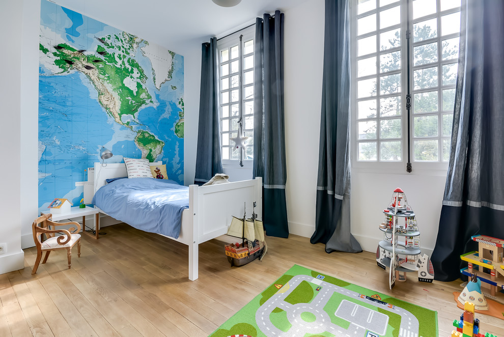 Photo of a large transitional kids' bedroom for kids 4-10 years old and boys in Paris with white walls and light hardwood floors.