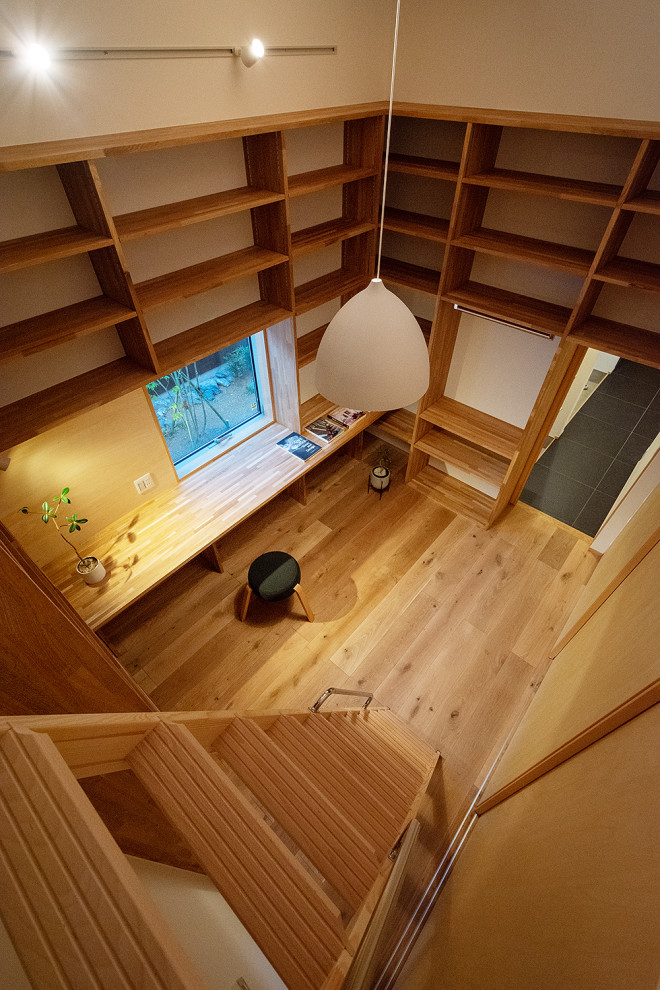 Imagen de despacho blanco nórdico pequeño sin chimenea con biblioteca, paredes blancas, suelo de madera en tonos medios, escritorio empotrado, suelo marrón, papel pintado y papel pintado