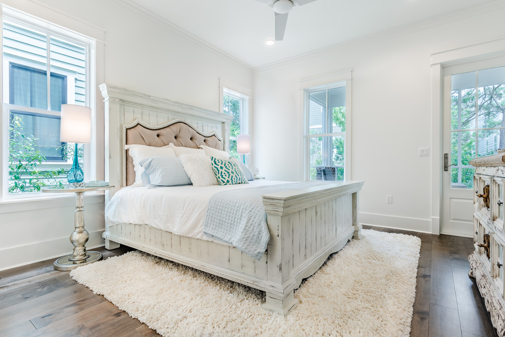 Mid-sized beach style guest bedroom in Other with white walls, dark hardwood floors, no fireplace and brown floor.