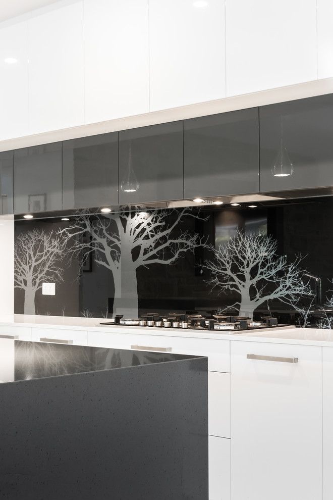 Mid-sized contemporary l-shaped kitchen pantry in Adelaide with a double-bowl sink, flat-panel cabinets, white cabinets, quartz benchtops, black splashback, glass sheet splashback, stainless steel appliances, ceramic floors and with island.