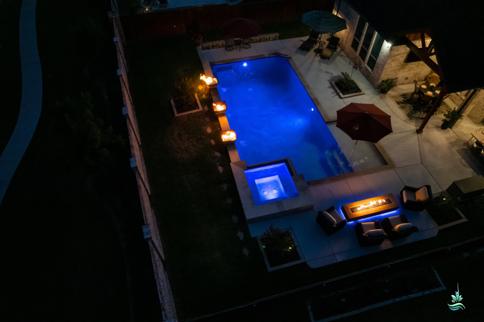 Esempio di una grande piscina naturale moderna personalizzata dietro casa con una vasca idromassaggio e lastre di cemento