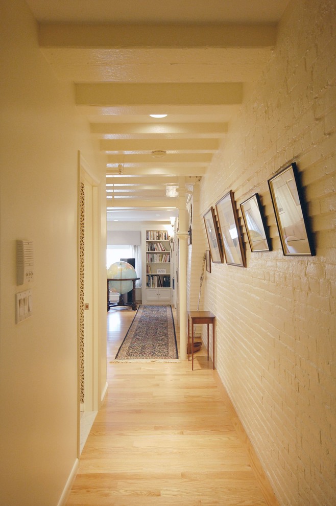 Inspiration for a mid-sized transitional hallway in Boston with white walls, light hardwood floors and beige floor.