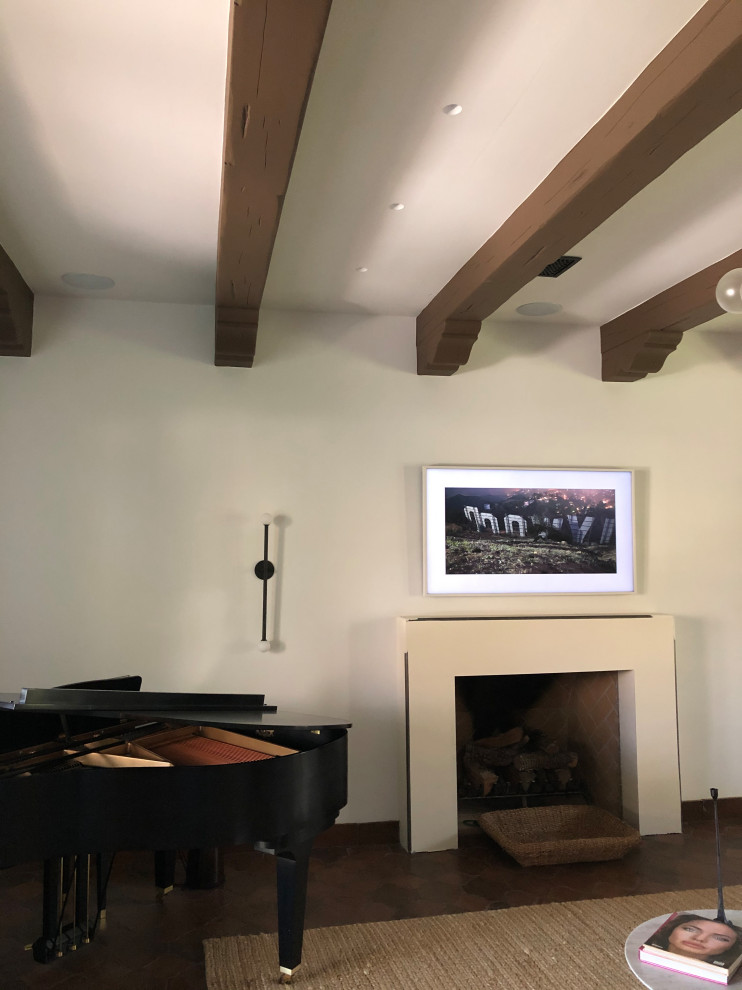 Inspiration for a mid-sized traditional formal open concept living room in Phoenix with white walls, terra-cotta floors, a standard fireplace, a plaster fireplace surround, a wall-mounted tv, red floor and exposed beam.
