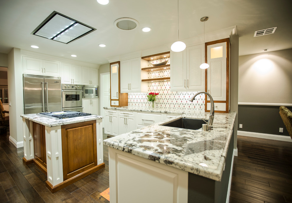 This is an example of a mid-sized contemporary u-shaped open plan kitchen in Los Angeles with an undermount sink, raised-panel cabinets, white cabinets, granite benchtops, red splashback, glass tile splashback, stainless steel appliances, dark hardwood floors and with island.