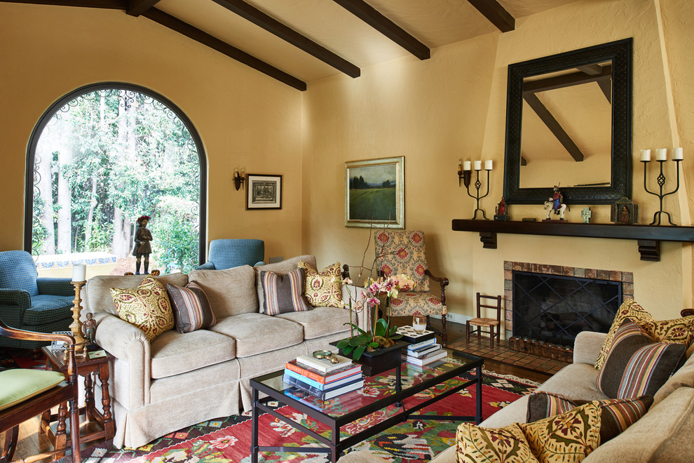 Inspiration for a large mediterranean formal enclosed living room in Los Angeles with beige walls, dark hardwood floors, a standard fireplace, a tile fireplace surround, no tv and brown floor.