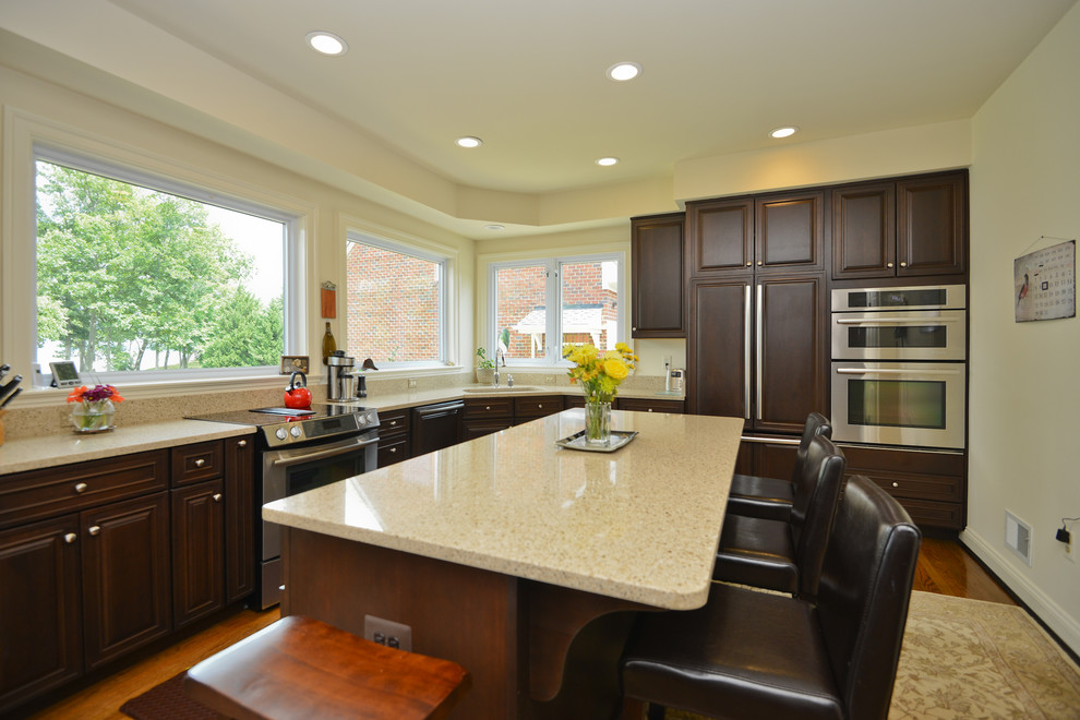 L-shaped dark wood floor eat-in kitchen photo in DC Metro with an undermount sink, raised-panel cabinets, dark wood cabinets, quartz countertops, paneled appliances and an island
