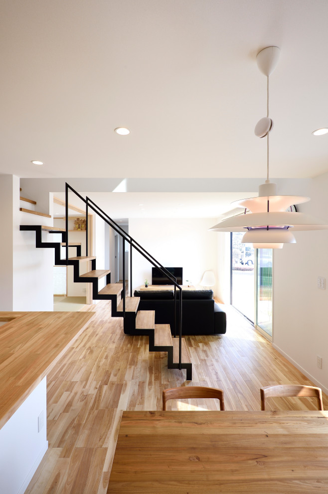 Inspiration for a mid-sized asian wood straight staircase in Other with open risers, metal railing and wallpaper.