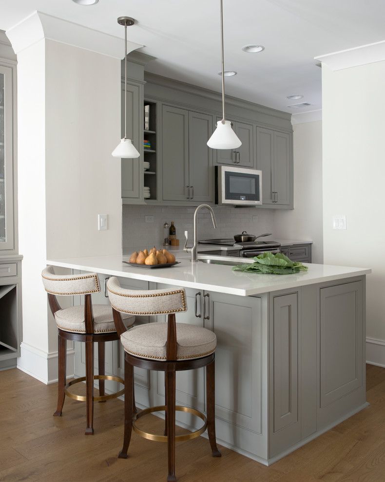 Design ideas for a transitional l-shaped kitchen in Atlanta with an undermount sink, recessed-panel cabinets, grey cabinets, white splashback, medium hardwood floors and a peninsula.