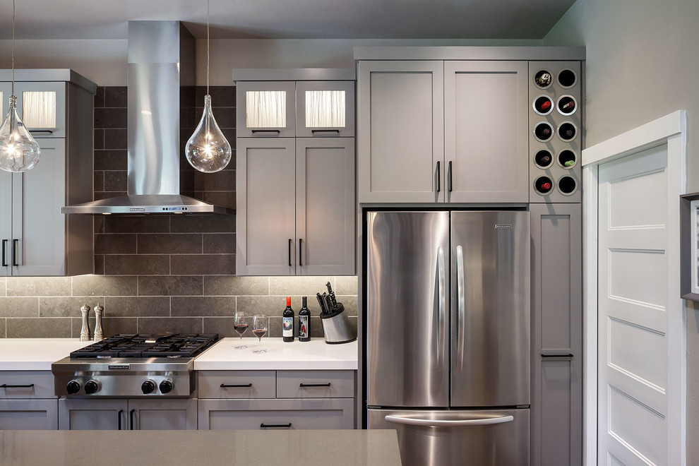 Inspiration for a large transitional l-shaped medium tone wood floor eat-in kitchen remodel with an undermount sink, shaker cabinets, gray cabinets, quartz countertops, gray backsplash, porcelain backsplash, stainless steel appliances and an island