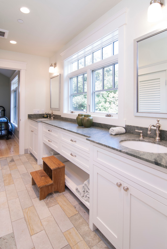 This is an example of a mid-sized transitional kids bathroom in San Francisco with an undermount sink, shaker cabinets, white cabinets, soapstone benchtops, an alcove tub, a shower/bathtub combo, a two-piece toilet, beige tile, porcelain tile, white walls and porcelain floors.