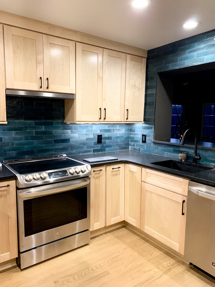 Inspiration for a mid-sized transitional u-shaped light wood floor and brown floor eat-in kitchen remodel with an undermount sink, shaker cabinets, light wood cabinets, granite countertops, blue backsplash, ceramic backsplash, stainless steel appliances, a peninsula and black countertops