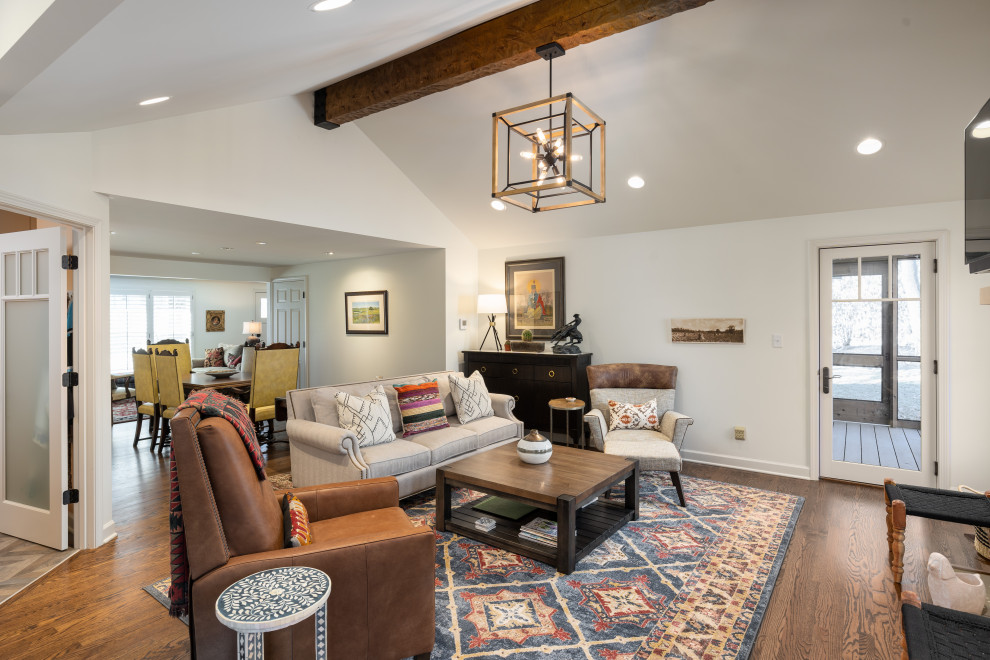 Large open concept family room in Kansas City with white walls, medium hardwood floors, a two-sided fireplace, a stone fireplace surround, a wall-mounted tv and vaulted.