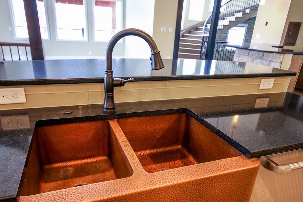 Example of a mid-sized transitional u-shaped light wood floor eat-in kitchen design with a farmhouse sink, flat-panel cabinets, dark wood cabinets, solid surface countertops, yellow backsplash, subway tile backsplash, stainless steel appliances and no island