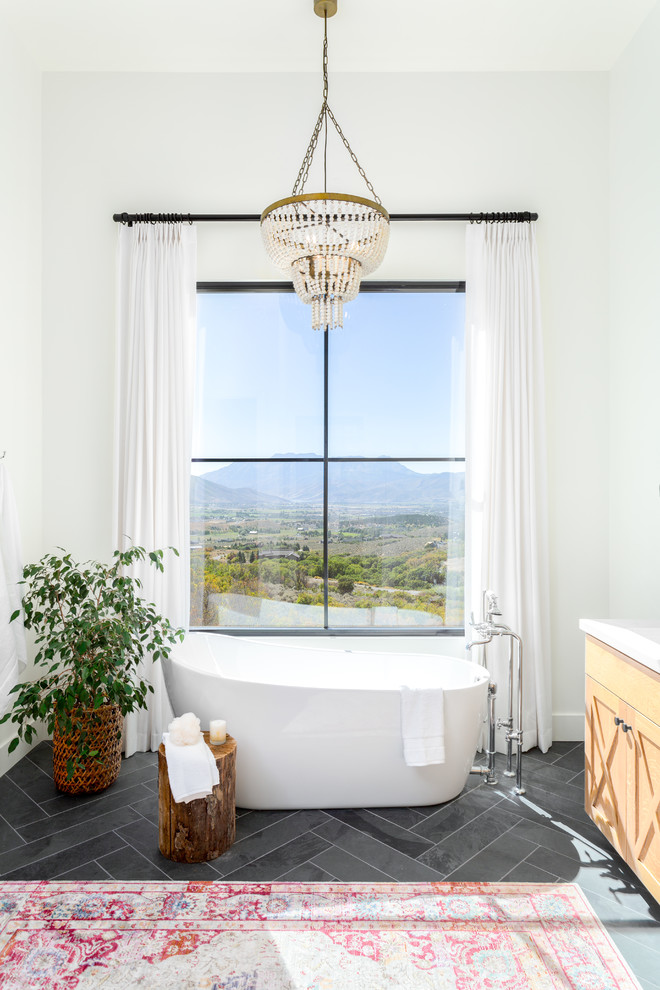 Design ideas for a large country master bathroom in Salt Lake City with shaker cabinets, light wood cabinets, a freestanding tub, white tile, marble benchtops, white benchtops, white walls, slate floors, an undermount sink and black floor.