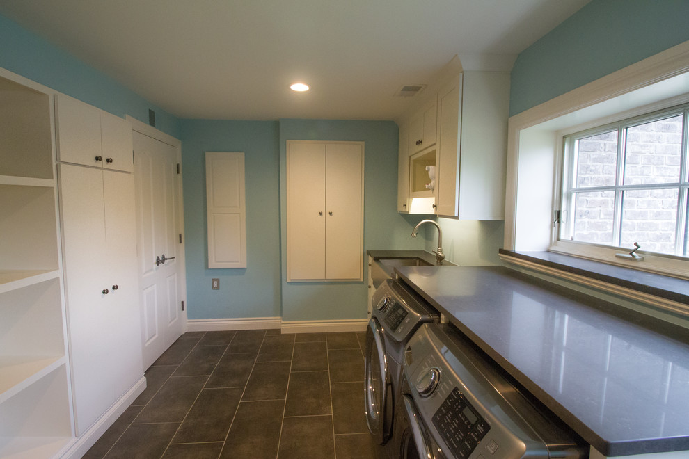 This is an example of a mid-sized transitional single-wall dedicated laundry room in Detroit with a farmhouse sink, shaker cabinets, white cabinets, soapstone benchtops, blue walls, ceramic floors and a side-by-side washer and dryer.