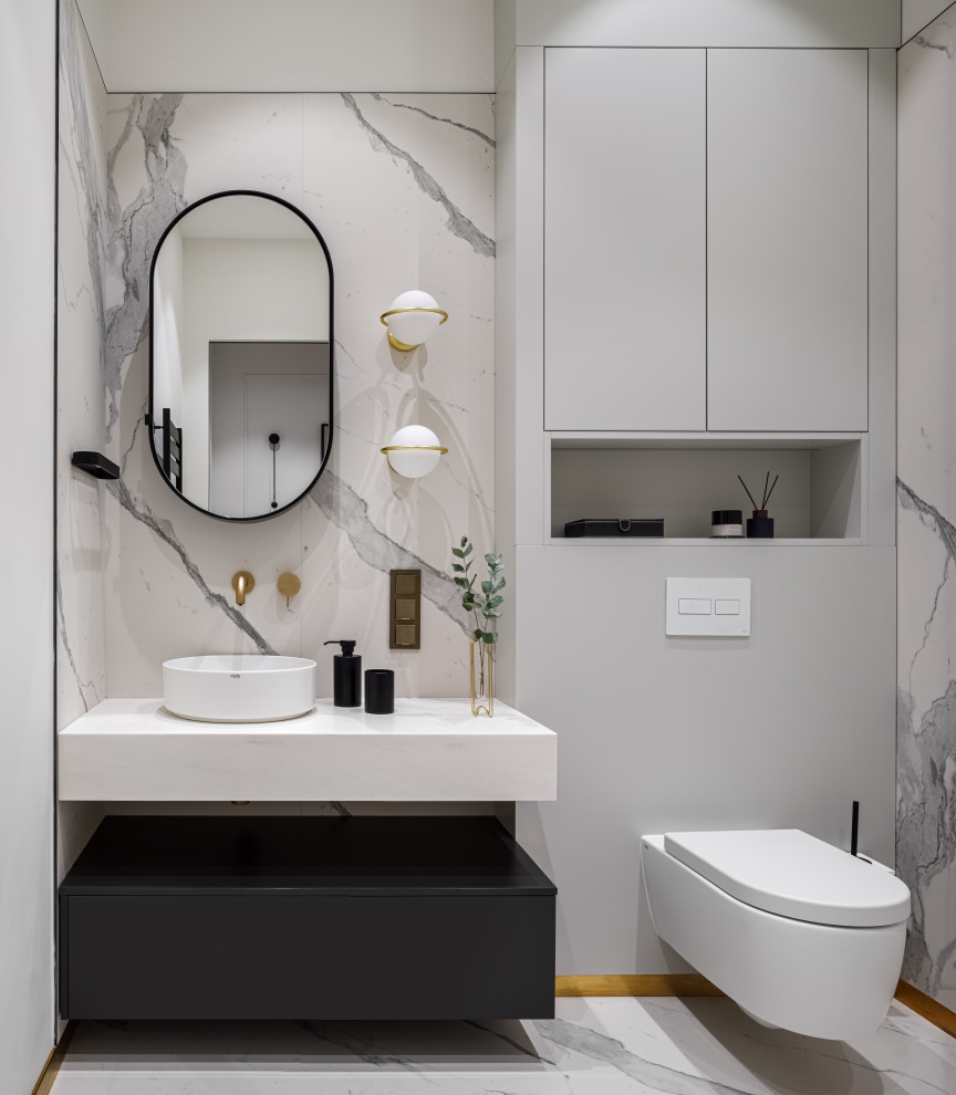 Foto på ett mellanstort funkis badrum med dusch, med luckor med infälld panel, svarta skåp, våtrum, en vägghängd toalettstol, vit kakel, marmorkakel, vita väggar, klinkergolv i porslin, ett väggmonterat handfat och vitt golv