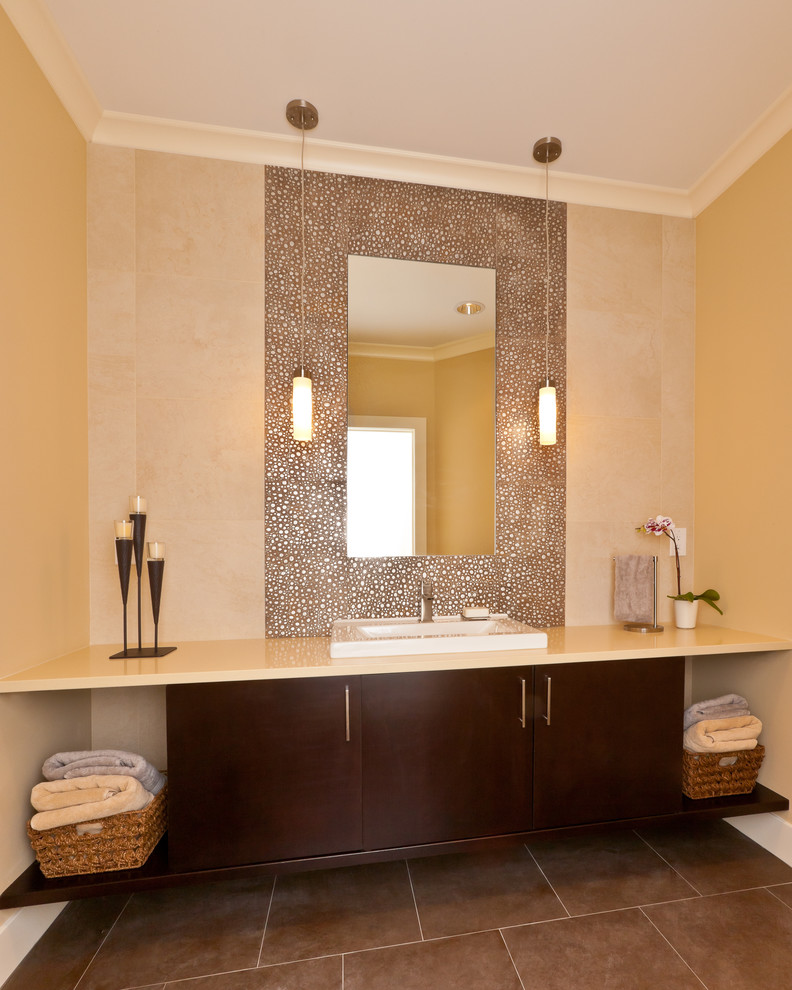 Photo of a contemporary powder room in Seattle with a drop-in sink, flat-panel cabinets, dark wood cabinets, solid surface benchtops, beige walls, brown tile and beige benchtops.