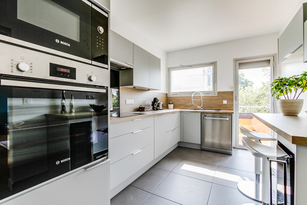 Idée de décoration pour une grande cuisine nordique en L fermée avec un évier 1 bac, un placard à porte affleurante, des portes de placard grises, un plan de travail en stratifié, une crédence beige, un électroménager noir, un sol en carrelage de céramique, aucun îlot, un sol gris et un plan de travail beige.