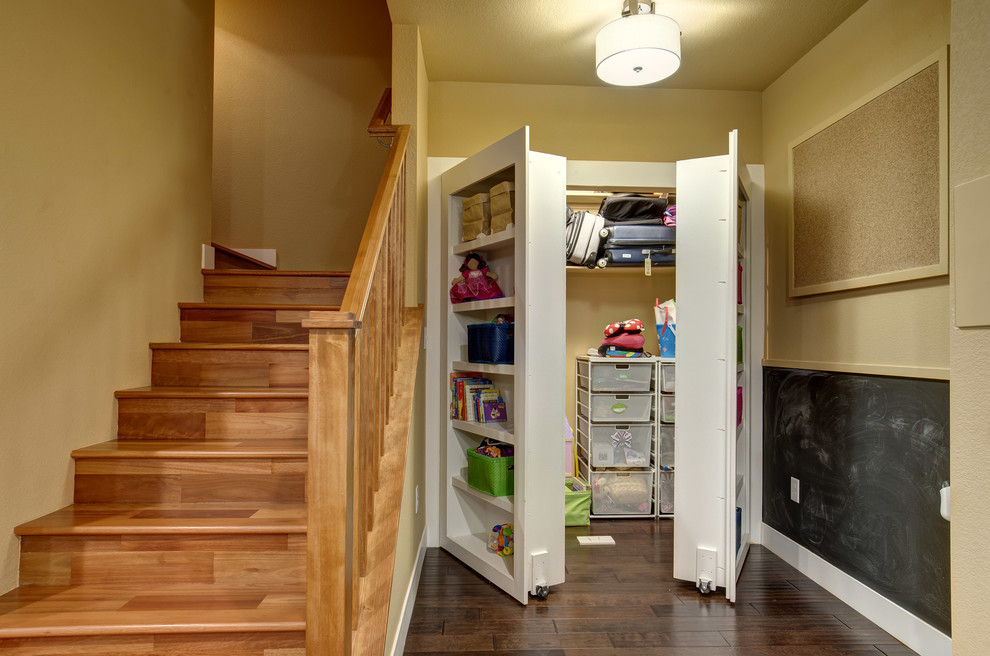 Photo of a mid-sized transitional gender-neutral built-in wardrobe in Denver with open cabinets, white cabinets, dark hardwood floors and brown floor.
