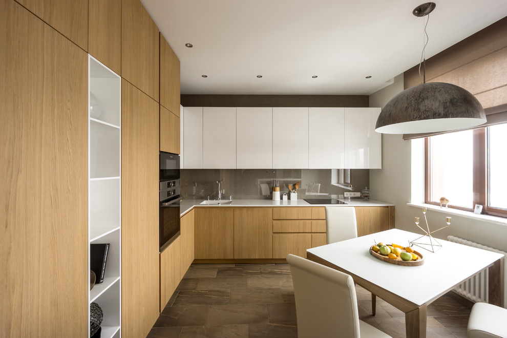 Mid-sized contemporary l-shaped eat-in kitchen in Moscow with an undermount sink, flat-panel cabinets, medium wood cabinets, solid surface benchtops, grey splashback, glass sheet splashback, stainless steel appliances, porcelain floors, no island, brown floor and white benchtop.