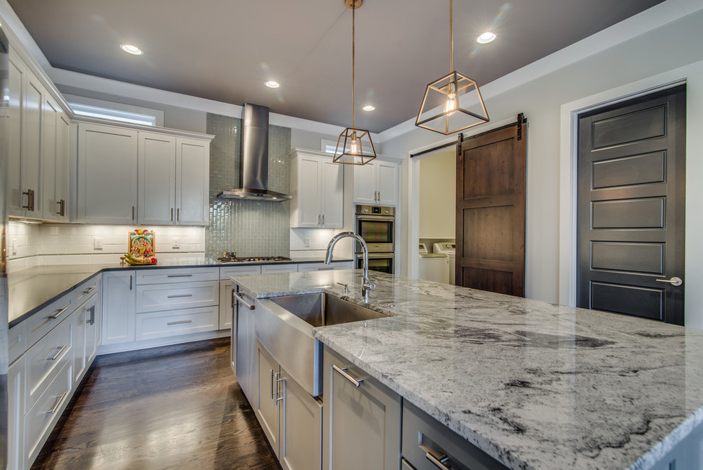 Transitional dark wood floor kitchen photo in Nashville with a farmhouse sink, white cabinets, white backsplash, stainless steel appliances and an island