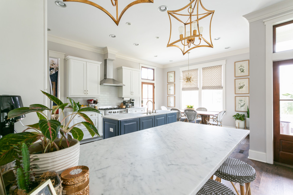 This is an example of a large traditional u-shaped eat-in kitchen in Charleston with an undermount sink, shaker cabinets, blue cabinets, granite benchtops, white splashback, subway tile splashback, stainless steel appliances, dark hardwood floors, multiple islands, brown floor and grey benchtop.