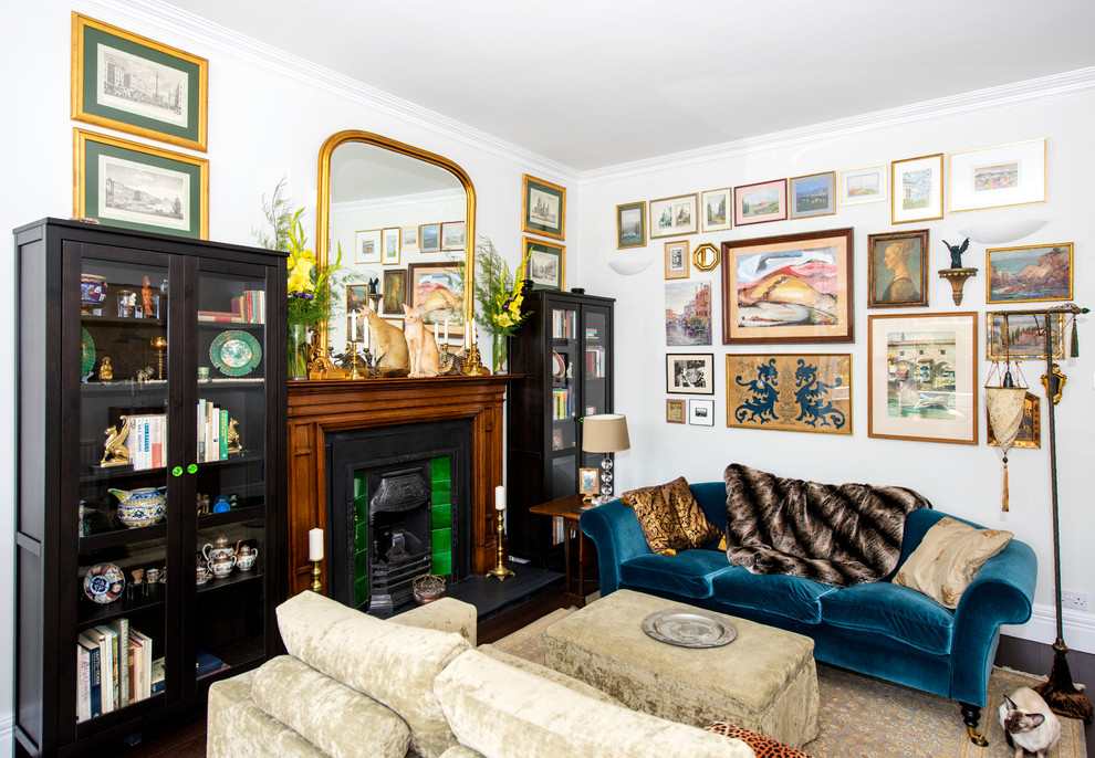This is an example of a mid-sized eclectic formal enclosed living room in Sussex with white walls, dark hardwood floors, a standard fireplace and no tv.
