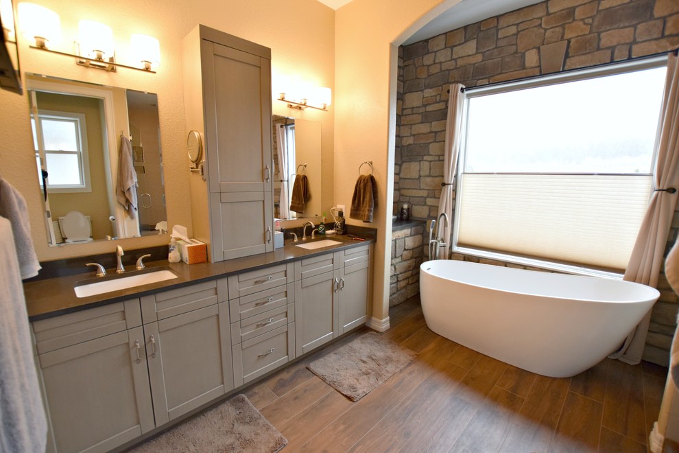 Photo of a large transitional master bathroom in Denver with recessed-panel cabinets, beige cabinets, a freestanding tub and an undermount sink.