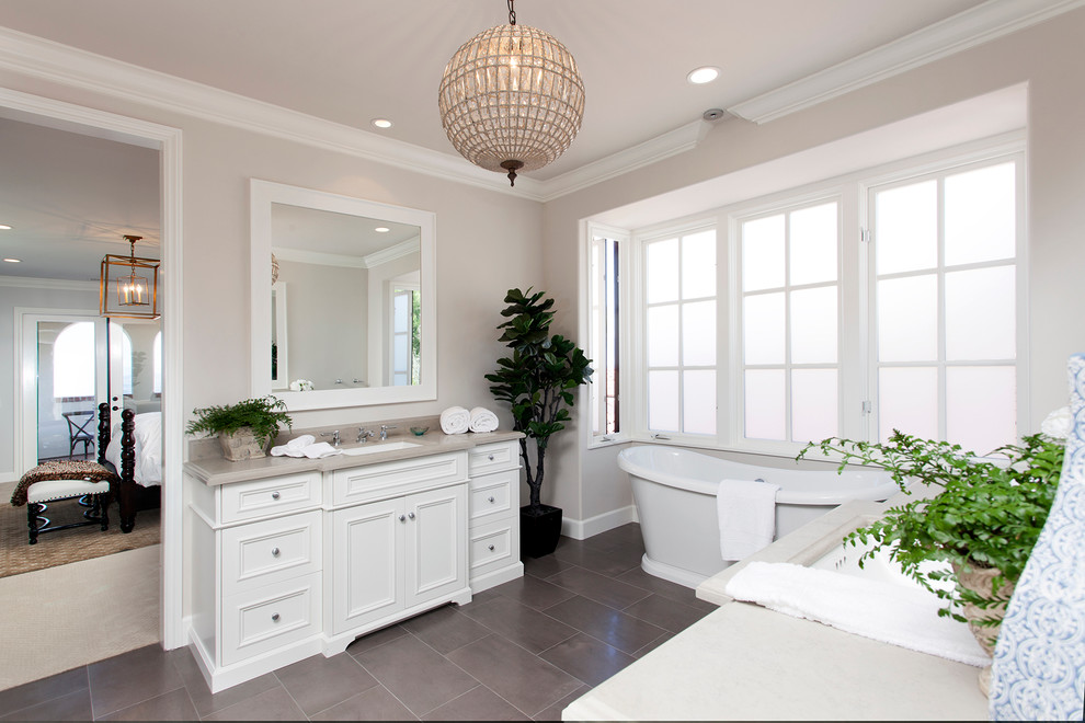 Inspiration for a transitional bathroom in Orange County with an undermount sink, recessed-panel cabinets, white cabinets, a freestanding tub, grey walls and beige benchtops.
