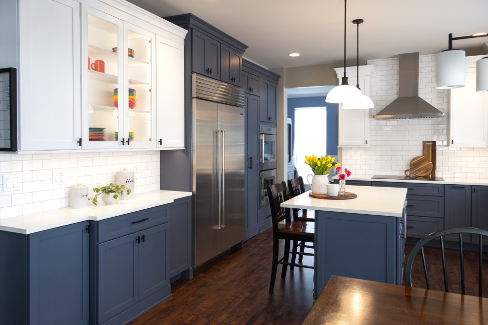 Inspiration for a medium sized traditional kitchen/diner in Chicago with shaker cabinets, blue cabinets, quartz worktops, white splashback, ceramic splashback, stainless steel appliances, an island and white worktops.