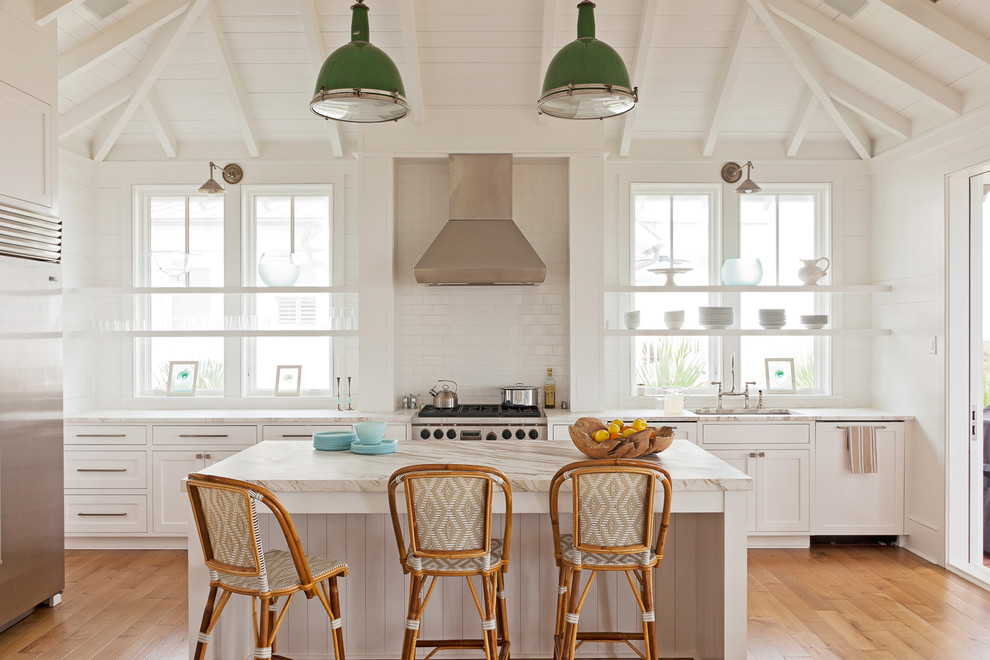 Design ideas for a beach style kitchen in Charleston with open cabinets, marble benchtops, white splashback, stainless steel appliances, medium hardwood floors, with island, an undermount sink and white cabinets.