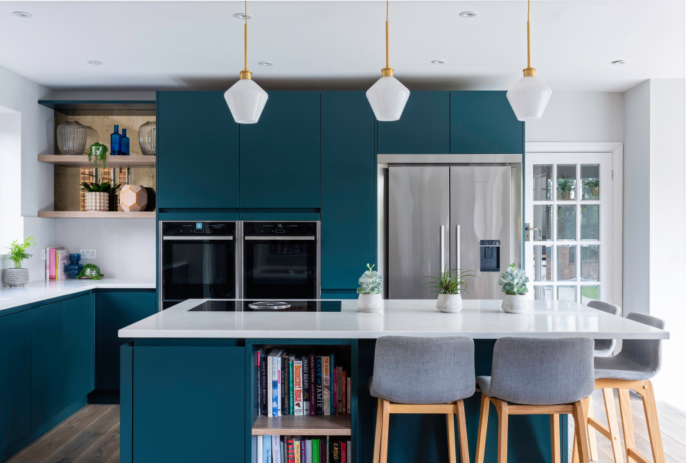 Photo of a contemporary l-shaped kitchen in Surrey with flat-panel cabinets, blue cabinets, white splashback, stainless steel appliances, dark hardwood floors, with island, brown floor and white benchtop.