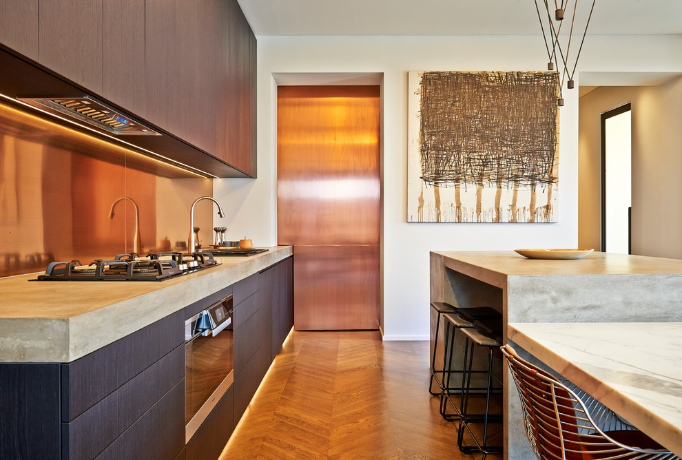 Photo of a mid-sized industrial single-wall kitchen in Adelaide with a double-bowl sink, flat-panel cabinets, dark wood cabinets, concrete benchtops, metallic splashback, metal splashback, medium hardwood floors and with island.