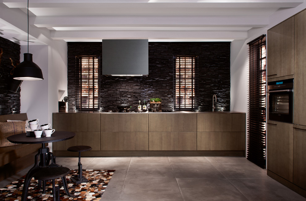 Design ideas for a large traditional single-wall eat-in kitchen in Munich with flat-panel cabinets, brown cabinets, stainless steel benchtops, brown splashback, black appliances, ceramic floors and no island.