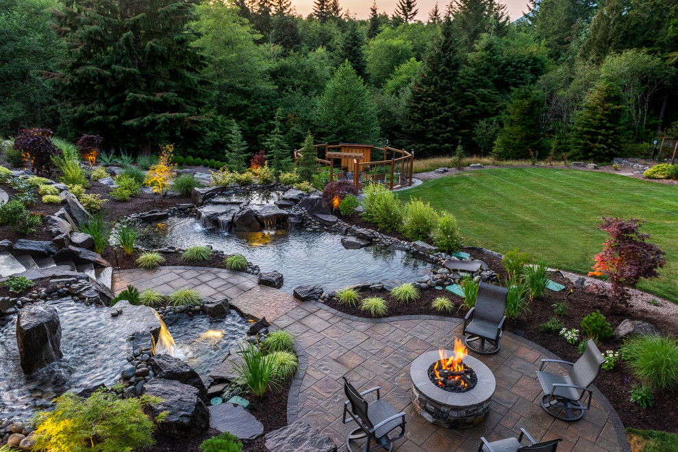 This is an example of an expansive arts and crafts backyard garden in Seattle with with waterfall and natural stone pavers.