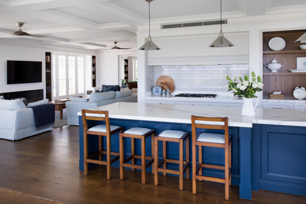Inspiration for a transitional galley open plan kitchen in Brisbane with marble benchtops, subway tile splashback, stainless steel appliances, with island, beaded inset cabinets, blue cabinets, white splashback, dark hardwood floors, brown floor and white benchtop.