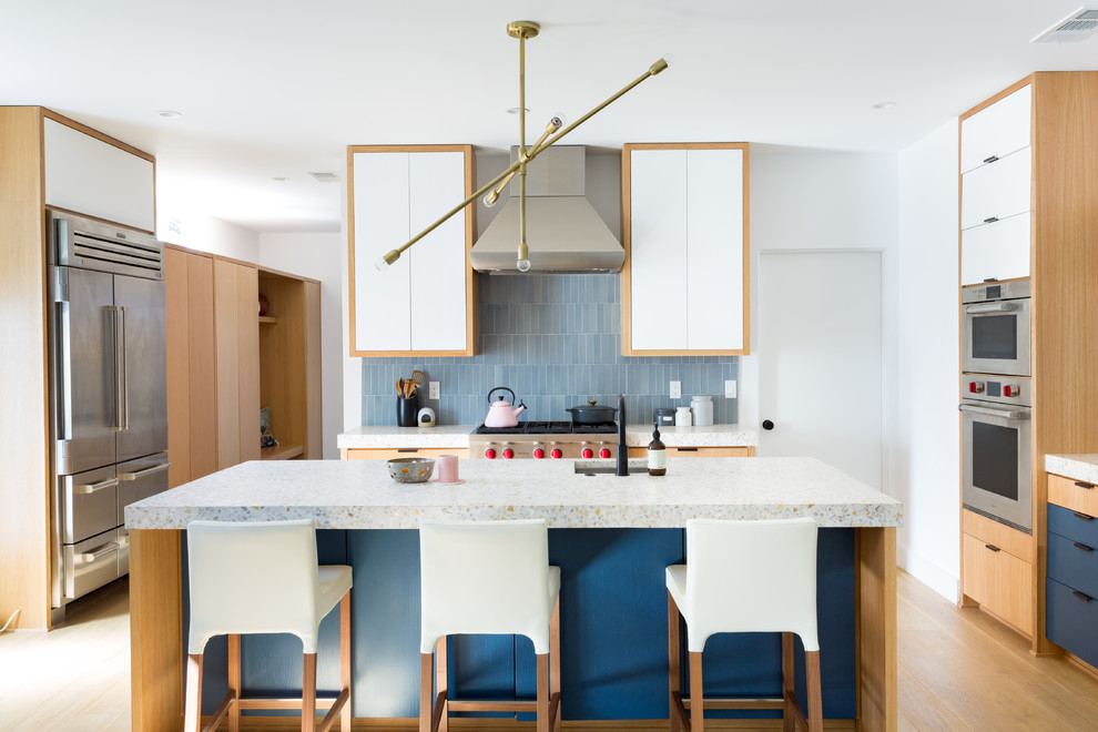 Inspiration for a large contemporary galley open plan kitchen in Los Angeles with an undermount sink, flat-panel cabinets, blue cabinets, concrete benchtops, blue splashback, ceramic splashback, stainless steel appliances, with island, medium hardwood floors, brown floor and white benchtop.