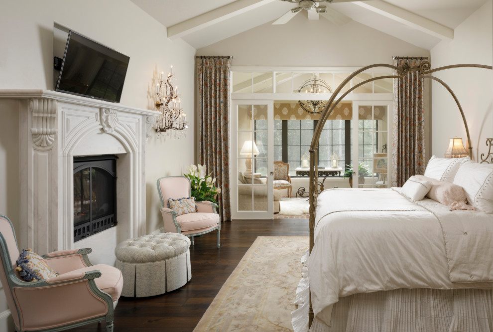 This is an example of a large master bedroom in Houston with white walls, dark hardwood floors, a standard fireplace, a stone fireplace surround, brown floor and vaulted.