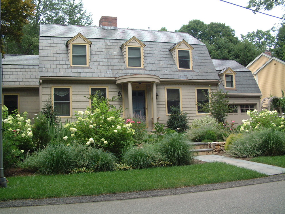 Photo of a small traditional one-storey beige house exterior in Boston with wood siding, a gambrel roof and a shingle roof.