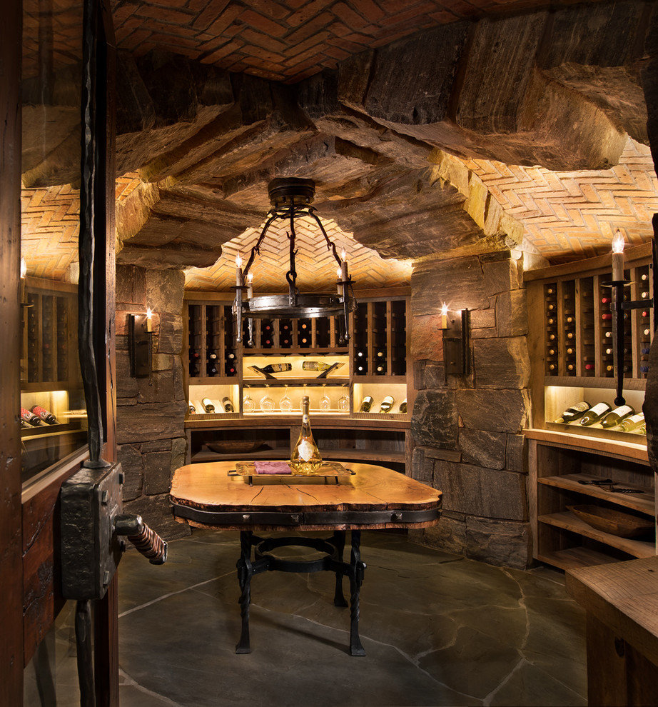 Photo of an expansive country wine cellar in Other with slate floors, display racks and grey floor.